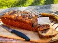 Delizioso banana bread vegano con gocce di cioccolato e mandorle, pronto per essere gustato all'aperto.