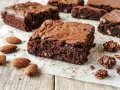 Brownies ricetta: quadrati di cioccolato fondente, umidi e ricchi, con mandorle intere e pezzetti croccanti di granola al cioccolato.