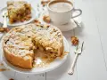 Torta con mandorle e zucchero a velo, perfetta per una ricetta frangipane. Accanto, una tazza di caffè e una fetta di torta.