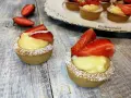 Deliziosi cestini alla frutta con crema pasticcera e fragole fresche, spolverati di zucchero a velo.
