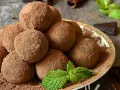 Pile di tartufi al cioccolato facili e veloci, spolverati di cacao, con menta fresca e un pezzetto di cioccolato fondente.