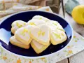 Cuore di biscotti al limone glassati, decorati con scorza di limone, su un piatto blu.
