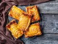 Sfogliatine di pasta sfoglia con zucchero e mele, dorate e lucide, su una griglia di raffreddamento.
