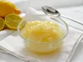 Una ciotola di deliziosa crema al limone senza uova, con limoni freschi affettati sullo sfondo.
