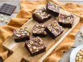 Deliziosi brownie senza glutine con nocciole tostate su tagliere di legno.