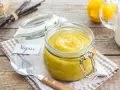 Crema pasticcera vegana in un barattolo di vetro, con bacche di vaniglia e limoni sullo sfondo.