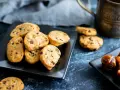 Biscotti vegan con gocce di cioccolato e datteri su piatti neri, pronti per una pausa golosa.
