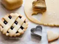 Una crostata con ripieno di marmellata, pasta frolla stesa e tagliabiscotti a forma di cuore.