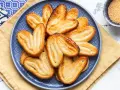 Un piatto blu pieno di croccanti ventagli di pasta sfoglia, dorati e zuccherati, pronti per essere gustati.
