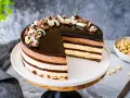 Una magnifica torta sette veli, con strati di mousse al cioccolato e crema, ricoperta da glassa lucida e riccioli di cioccolato.