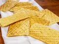 Un mucchio di croccanti ferratelle abruzzesi, dolci tradizionali, disposte su un panno bianco su un tavolo di legno.