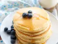 Pancakes soffici con albumi, guarniti con mirtilli freschi e sciroppo d'acero. Un dolce inizio di giornata.