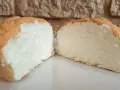 Una fetta di torta nuvola, soffice e leggera, con una crosticina dorata e un interno bianco e arioso.