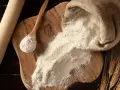 Farina 0 al posto della 00 nei dolci: un sacco di farina, un mestolo e spighe di grano su un tagliere di legno.