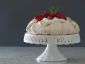 Pavlova ricetta: meringa croccante fuori e morbida dentro, guarnita con panna montata e fragole fresche.