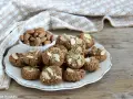 Biscotti senza zucchero, dorati e croccanti, guarniti con mandorle a lamelle. Accanto, una ciotola piena di mandorle intere.