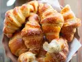 Brioches fatte in casa, dorate e soffici, cosparse di zucchero a velo. Un profumo invitante che ricorda la colazione perfetta.