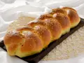 Treccia dorata di dolci con farina manitoba, cosparsa di granella croccante, su un letto di lino bianco.