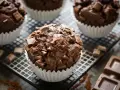 Muffin al cioccolato ricchi e golosi, con gocce e pezzi di cioccolato fondente, su una griglia con cacao e tavolette di cioccolato.