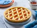 Crostata alla marmellata dorata, perfetta per il tempo cottura crostata forno statico. Servita su un piatto di marmo con tovagliolo blu.