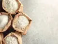 Sacchetti di carta aperti pieni di diverse farine, tra cui farina 0 e manitoba, pronte per creare pane e dolci.