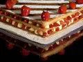Un invitante millefoglie cake con strati di crema pasticcera e fragole fresche, decorato con fragole intere e zucchero a velo.