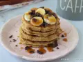 Pancake light con banana, cioccolato e sciroppo d'acero su un piatto rosa.