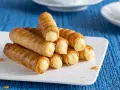 Un mucchio di cannoncini alla crema dorati, ripieni di una crema pasticcera liscia e invitante, pronti per essere gustati.