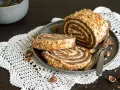 Rotolo alla Nutella ricoperto di granella di nocciole, servito su un piatto con due fette tagliate.
