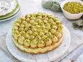 Torta rotonda con tante piccole meringhe verdi, guarnite con granella di pistacchio. Un delizioso tiramisù al pistacchio pronto per essere gustato.