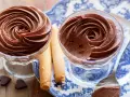 Deliziosa mousse al cioccolato in coppette di vetro, accompagnata da biscotti arrotolati e cuoricini di cioccolato.