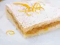 Fetta di crostata di frutta con pasta frolla, guarnita con zucchero a velo e scorza d'arancia. Perfetta per uno stampo da 28 cm.