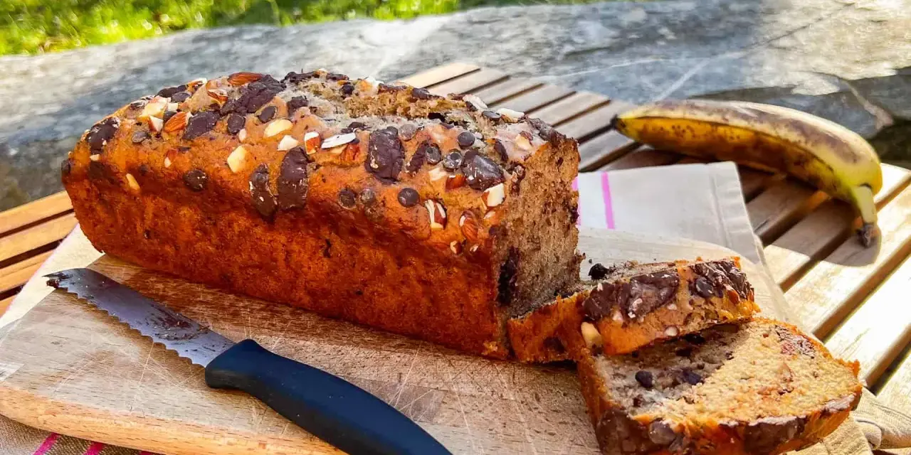 Delizioso banana bread vegano con gocce di cioccolato e mandorle, pronto per essere gustato all'aperto.