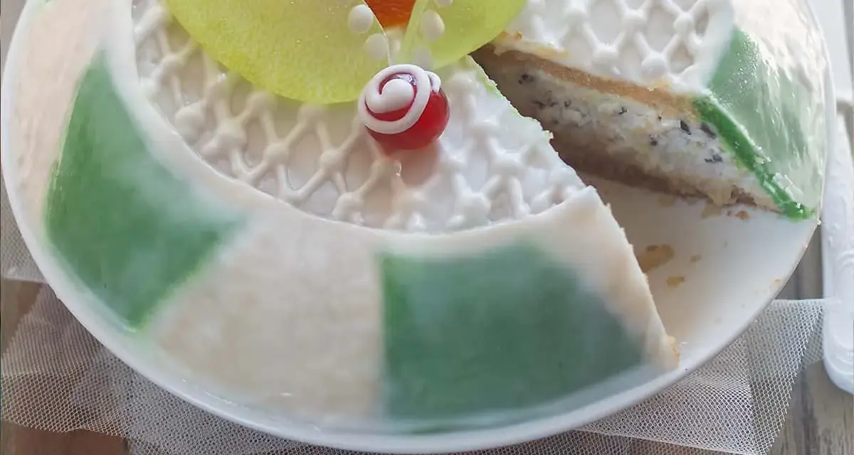 Una fetta di cassata siciliana palermitana, con decorazioni in glassa bianca e canditi colorati, mostra il suo ripieno cremoso.