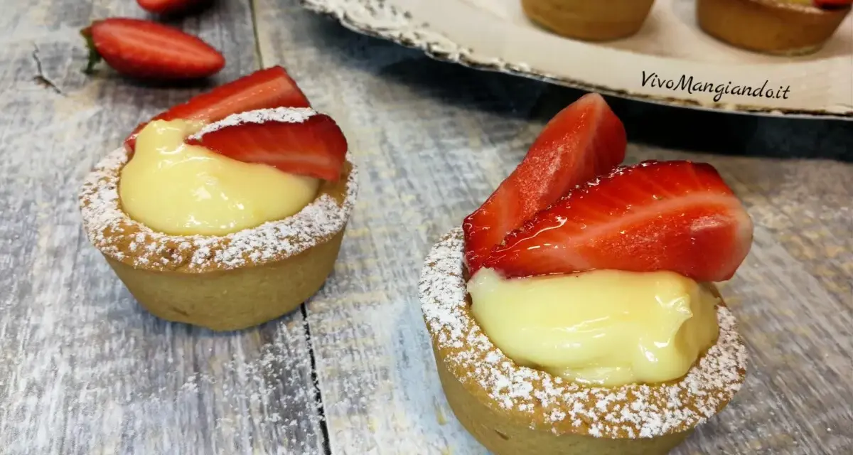 Deliziosi cestini alla frutta con crema pasticcera e fragole fresche, spolverati di zucchero a velo.