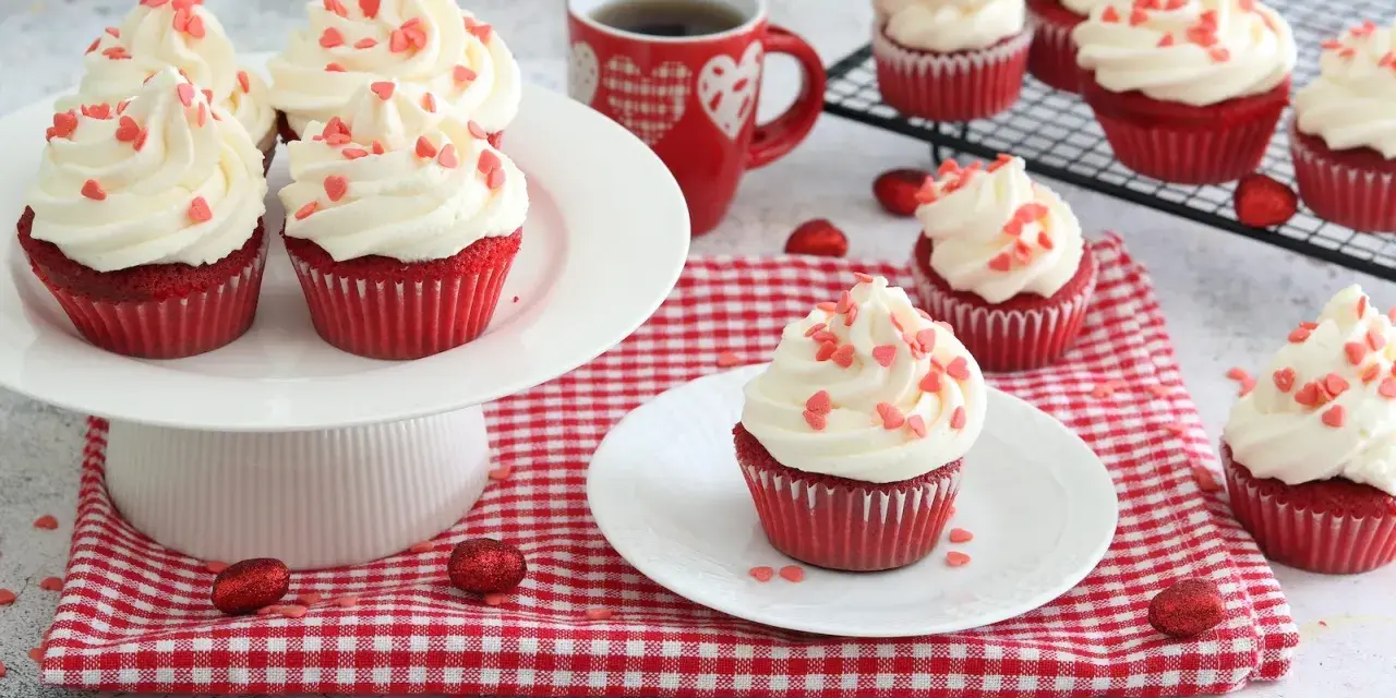 Deliziosi muffin red velvet con glassa bianca e cuoricini rossi, perfetti per San Valentino.