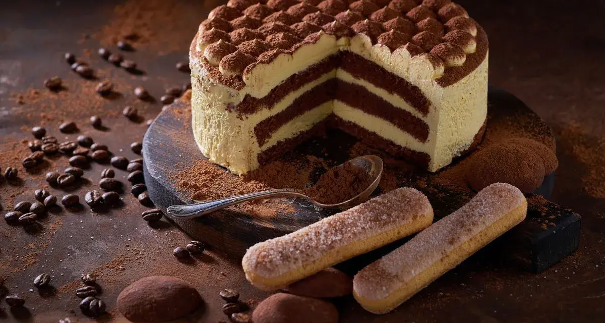 Una deliziosa torta tiramisù, con strati di crema e cacao, circondata da chicchi di caffè e savoiardi.