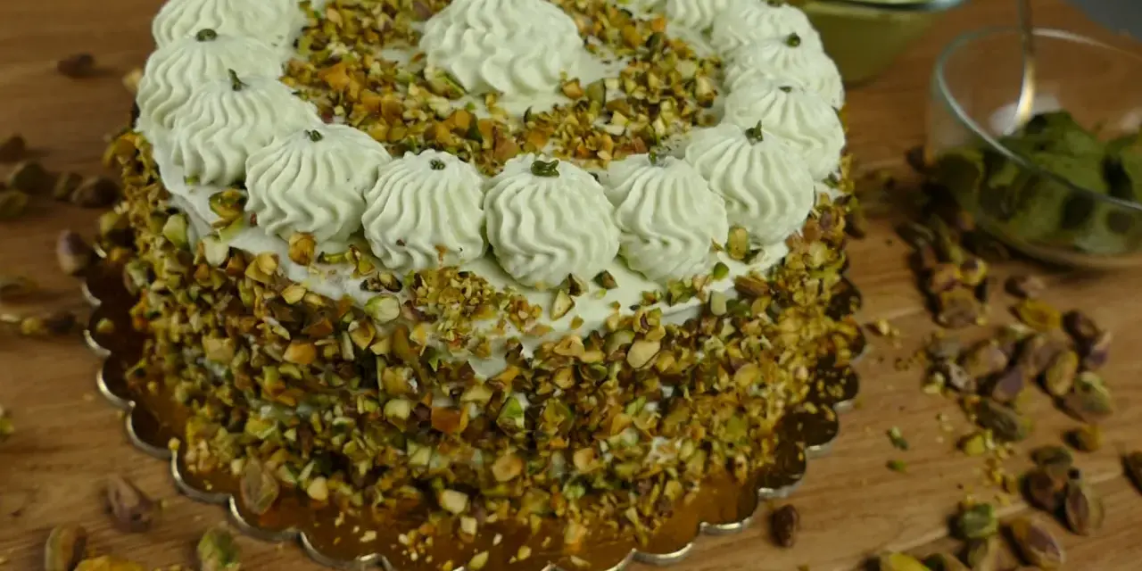 Delizioso dolce con crema al pistacchio già pronta, ricoperto di granella di pistacchi e decorato con ciuffi di crema.