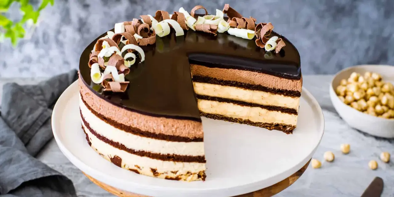 Una magnifica torta sette veli, con strati di mousse al cioccolato e crema, ricoperta da glassa lucida e riccioli di cioccolato.