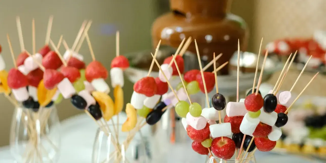 Spiedini di frutta e marshmallow pronti per essere intinti nella fontana di cioccolato come funziona.