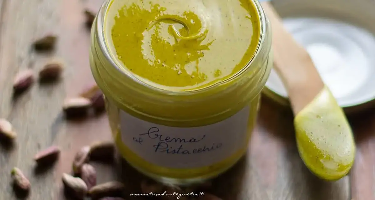 Vasetto di crema di pistacchio fatta in casa, con pistacchi sparsi intorno. La ricetta perfetta per una delizia!