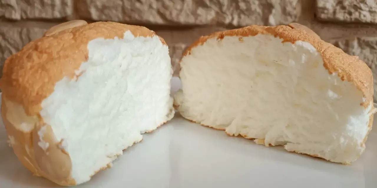 Una fetta di torta nuvola, soffice e leggera, con una crosticina dorata e un interno bianco e arioso.