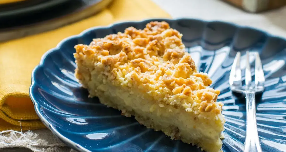 Fetta di sbrisolona con crema pasticcera su piatto blu, con forchetta trasparente.