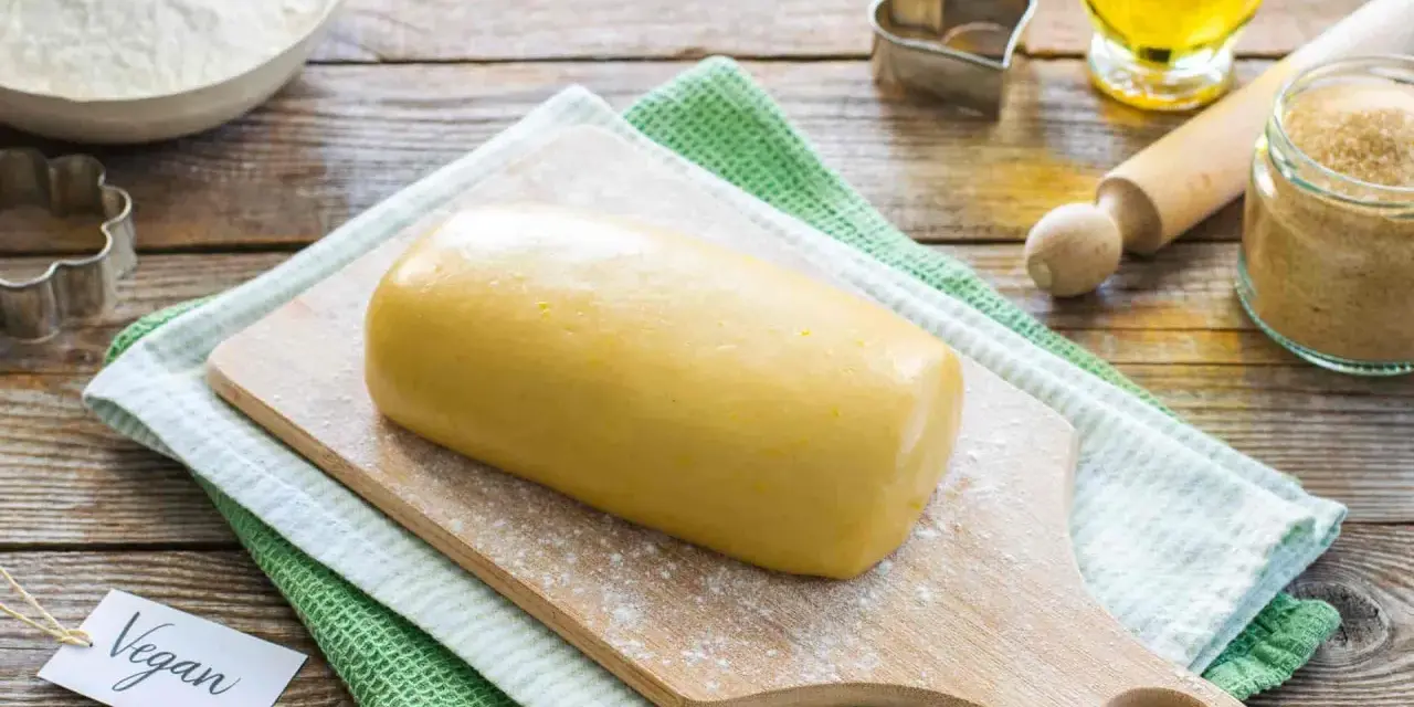 Impasto giallo pronto per biscotti, con un'etichetta "Vegan" e ingredienti come farina, zucchero e olio.