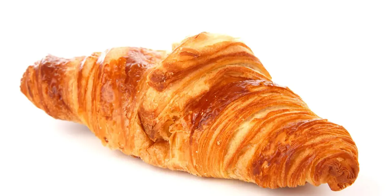 Un delizioso croissant francese, dorato e sfogliato, pronto per una colazione da sogno.