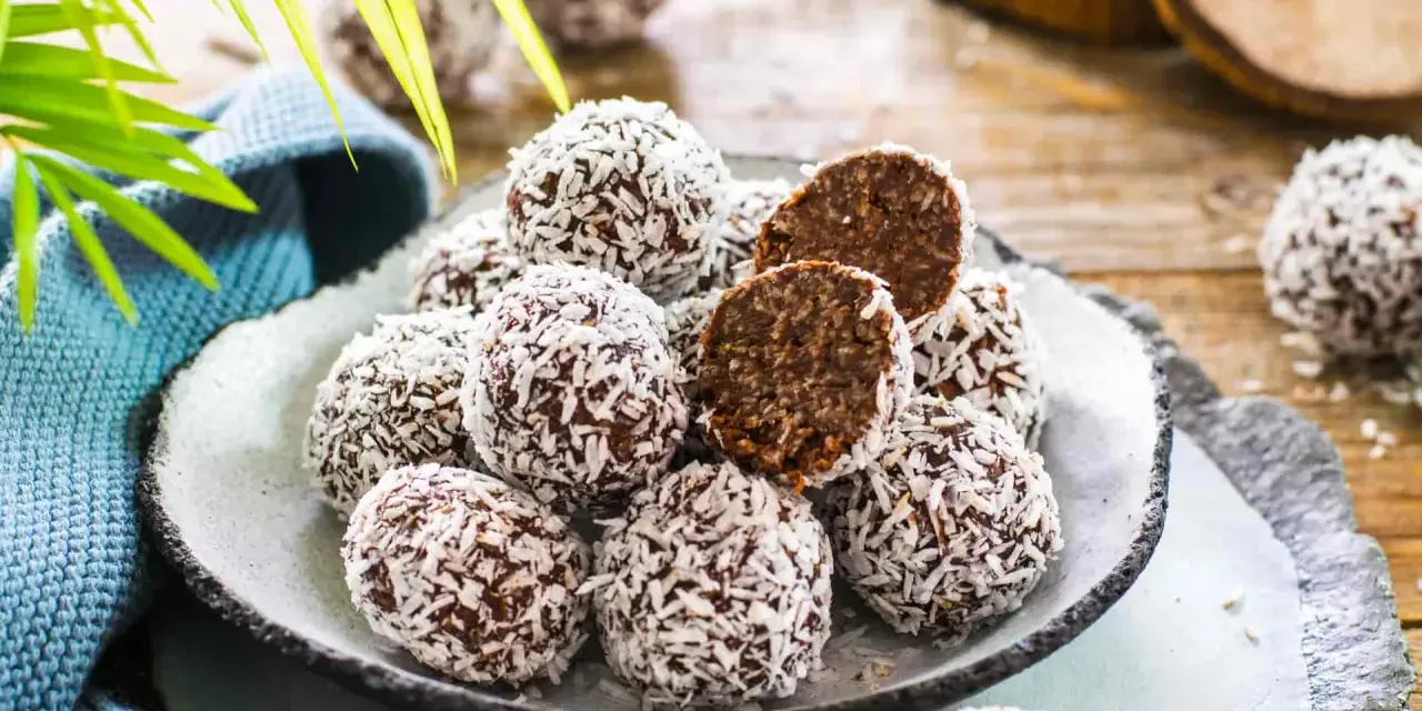 Praline al cioccolato facili e veloci, ricoperte di cocco grattugiato. Un morso rivela un interno morbido e goloso.