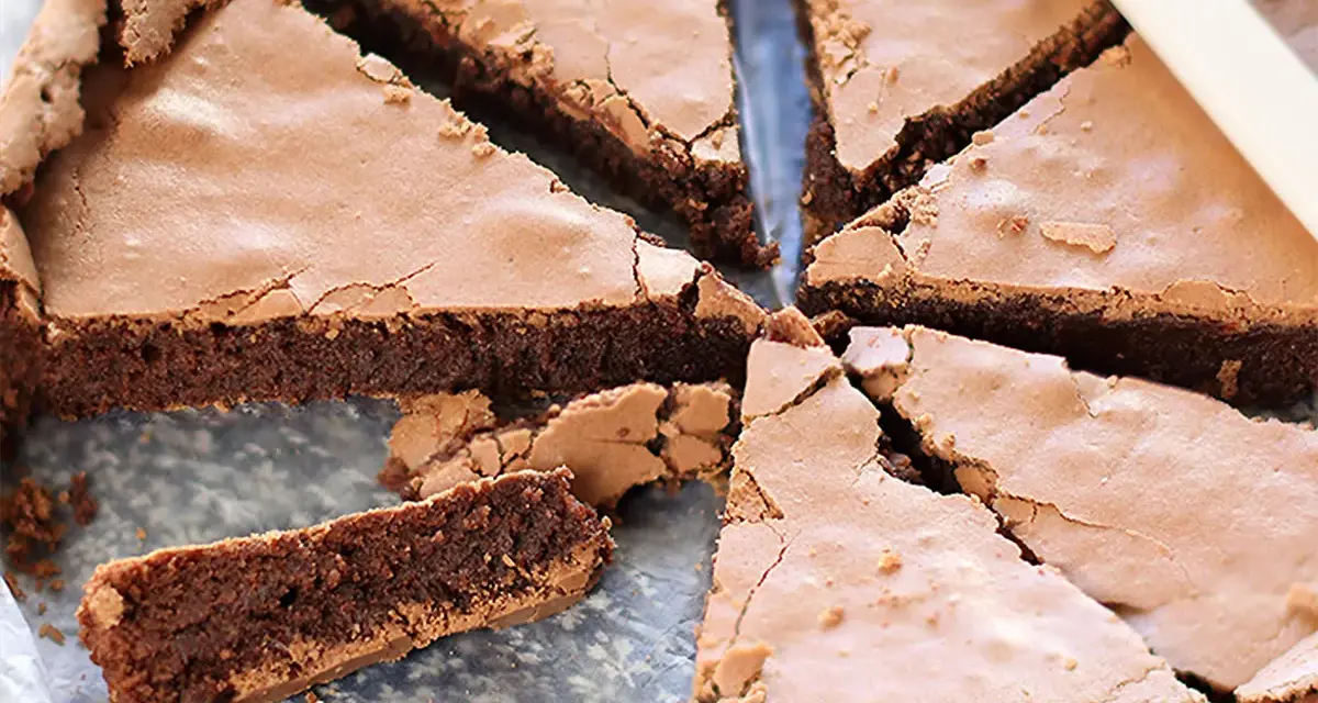 Torta tenerina con cuore morbido, tagliata a fette triangolari. La superficie è leggermente screpolata, rivelando la consistenza umida e golosa.