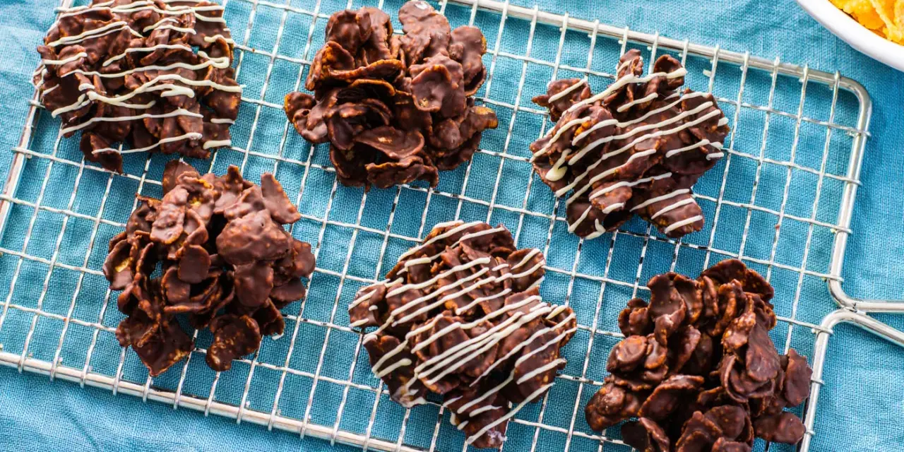 Dolcetti croccanti al cioccolato, simili a rose del deserto ricetta, su una griglia di raffreddamento. Alcuni sono decorati con cioccolato bianco.