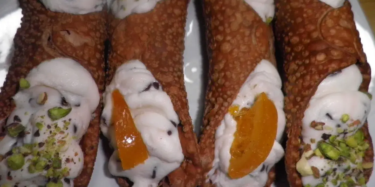 Cannoli siciliani con ripieno cremoso, gocce di cioccolato e pistacchi. Una ricetta semplice per un dolce irresistibile.