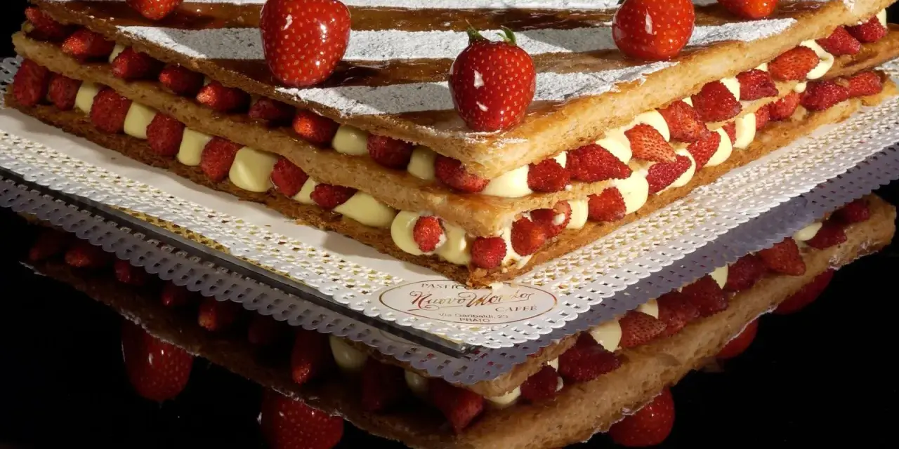 Un invitante millefoglie cake con strati di crema pasticcera e fragole fresche, decorato con fragole intere e zucchero a velo.